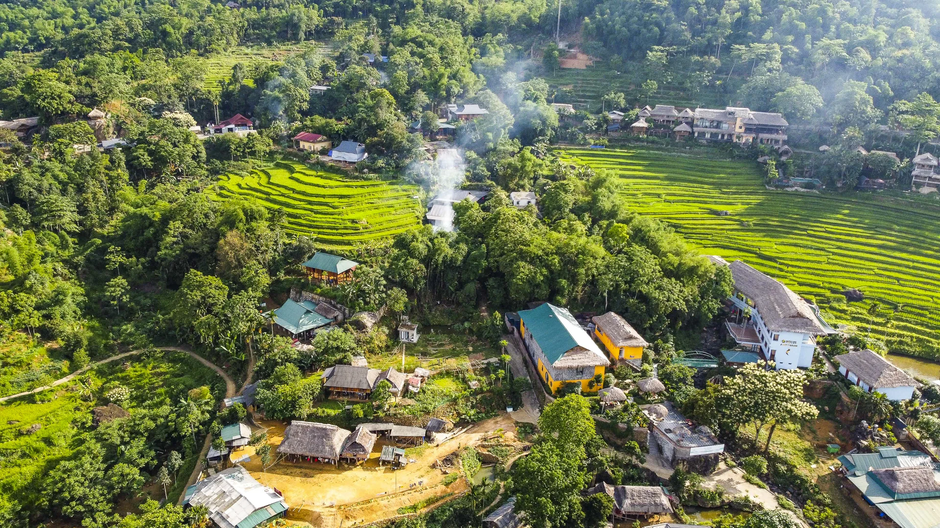 Những mái nhà sàn lợp lá cọ nằm nép mình bên sườn núi, bao quanh là màu xanh mát của núi rừng, tạo nên khung cảnh mộc mạc mà yên bình.