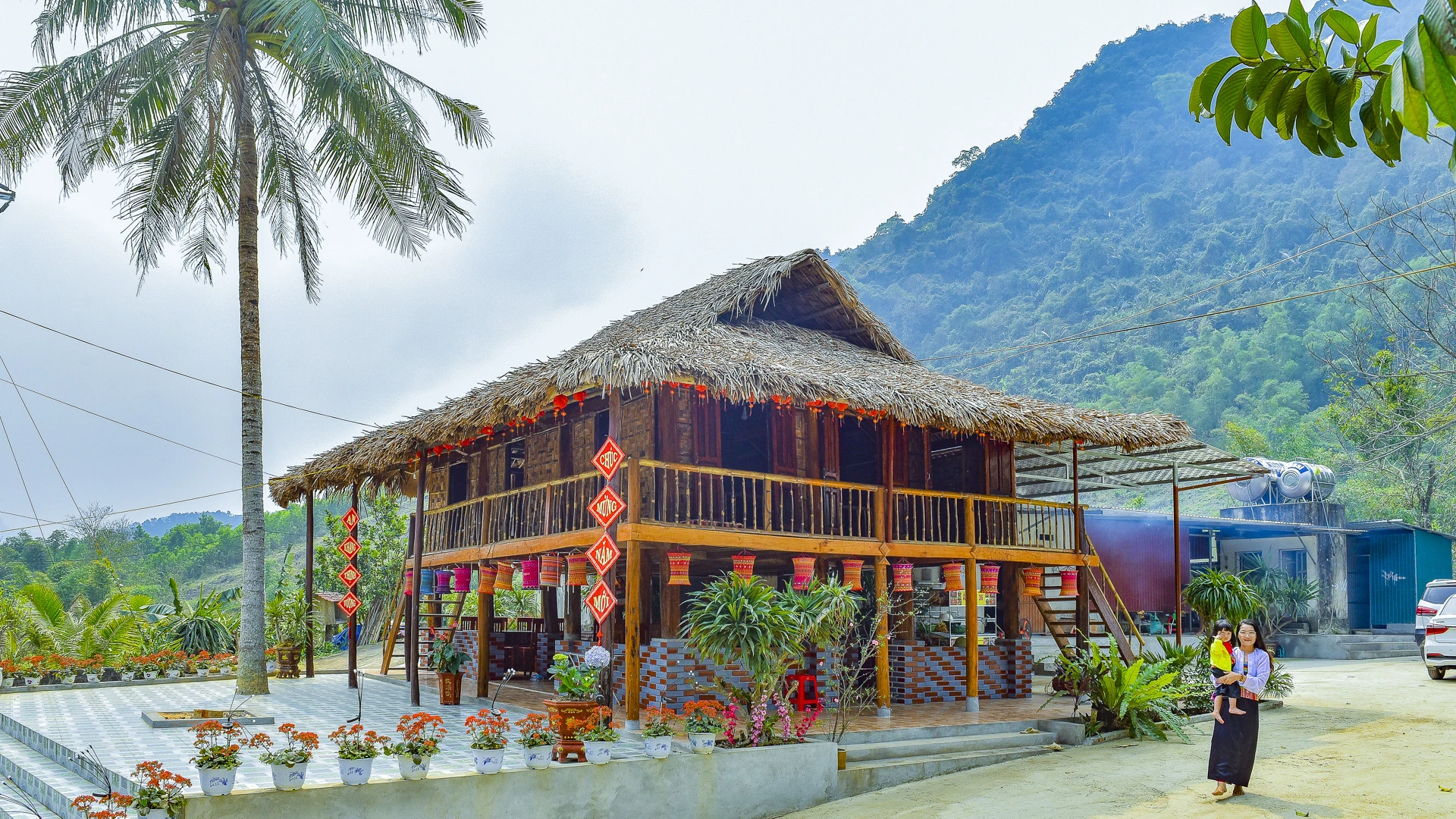 Những nếp nhà sàn bằng gỗ mộc mạc, mái lợp lá cọ rêu phong nằm nép mình bên sườn núi, vừa giữ được dáng vẻ truyền thống vừa hòa hợp với cảnh quan thiên nhiên.