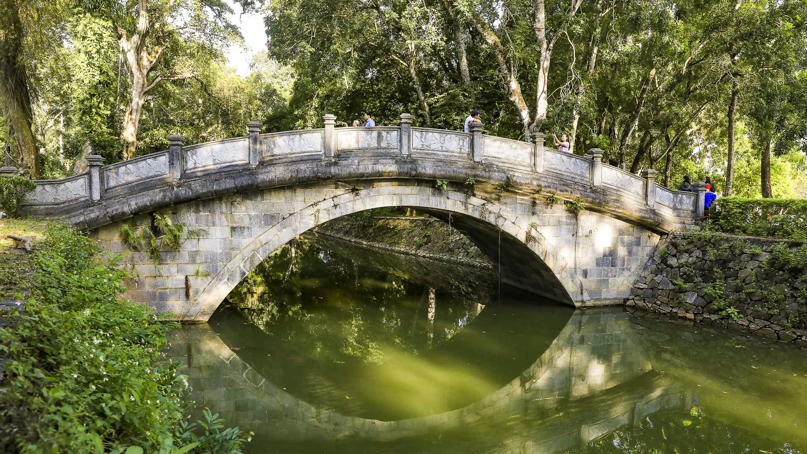 Trước lối vào hoàng thành là sông Ngọc - con sông đào mềm mại như dải lụa xanh, khởi nguồn từ Tây Hồ. Bắc ngang sông Ngọc là Tiên Loan Kiều, cây cầu cánh cung thanh thoát, dẫn bước khách qua dòng nước xanh thẳm, tiến thẳng vào trung tâm chính điện Lam Kinh.