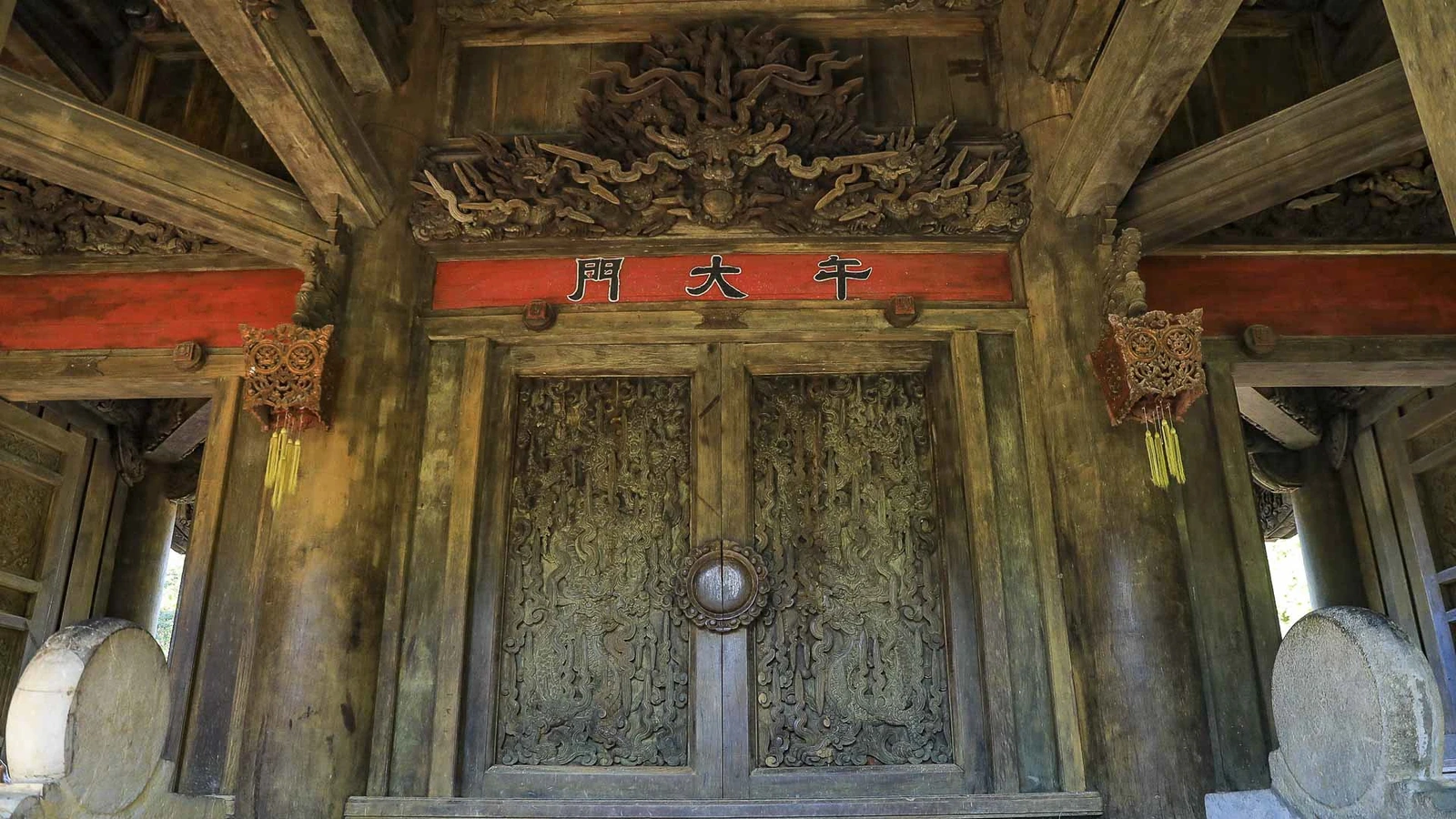 Trên các cánh cửa Ngọ môn, những đường chạm khắc tinh xảo uốn lượn, khắc họa hoa văn và linh vật với nét chạm sâu, mềm mại, khiến gỗ như bừng sống dưới ánh nắng sớm.