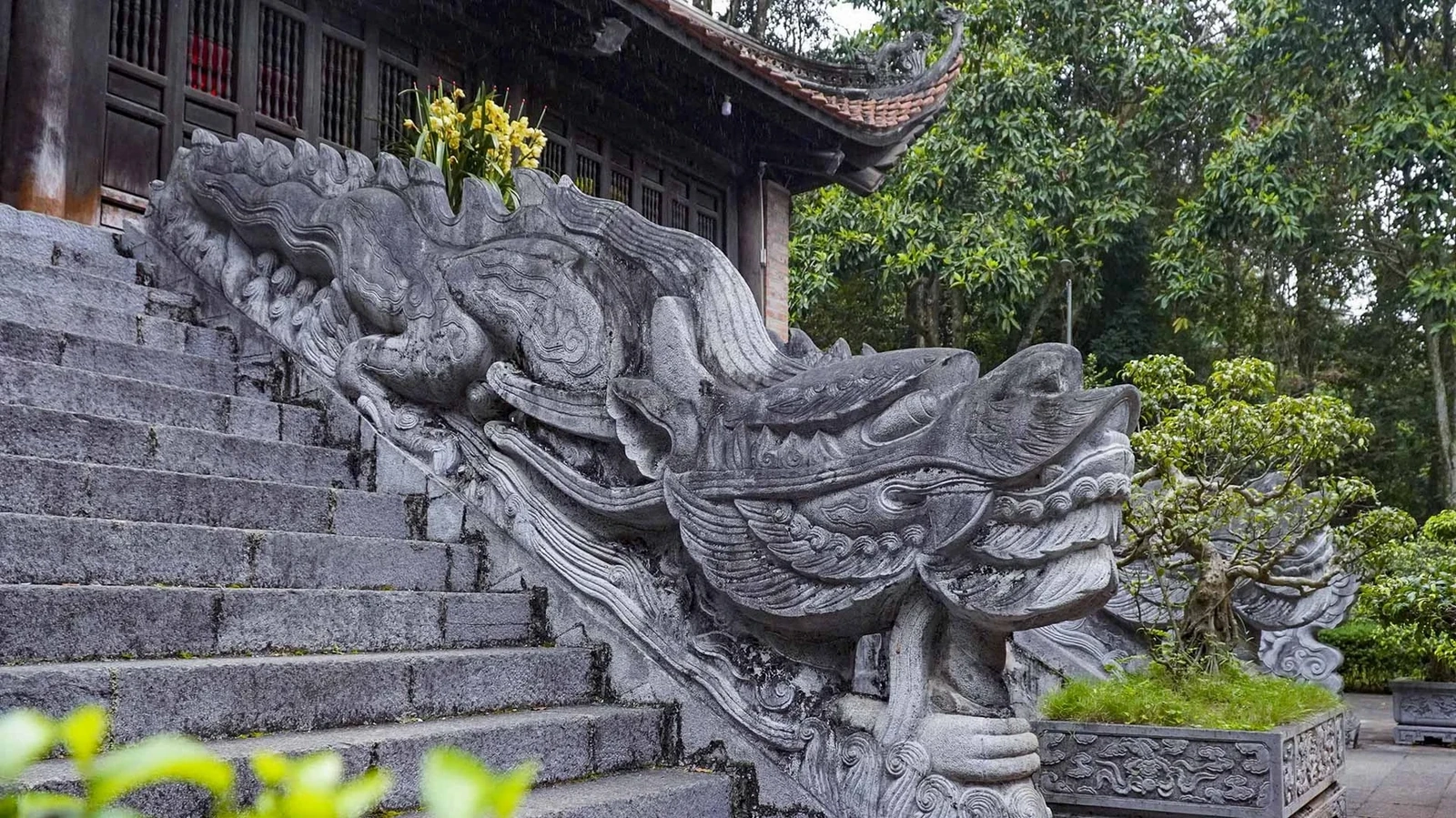 Lối bậc thềm dẫn lên hậu cung nổi bật với cặp rồng đá xanh tạc nguyên khối, tạo vẻ uy nghi cho toàn bộ công trình.