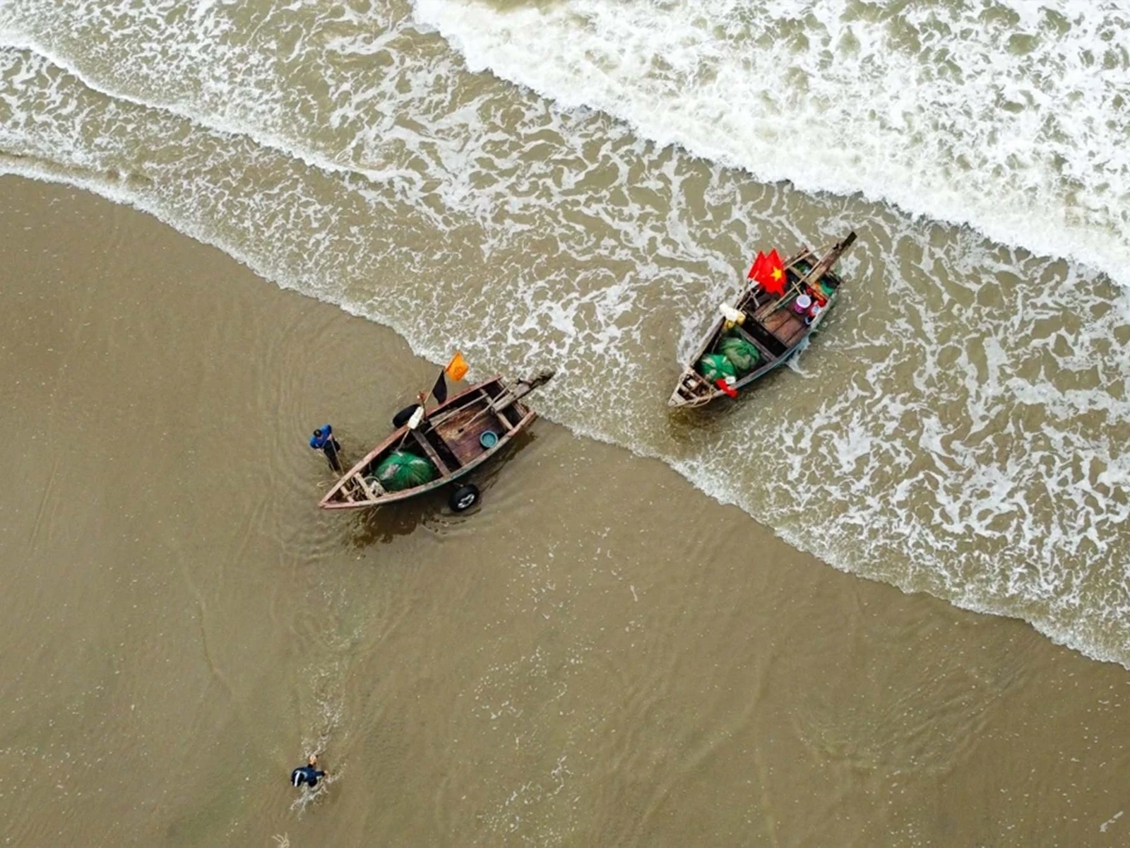 Ngư dân Sầm Sơn hối hả làm việc bên bờ biển khi thủy triều xuống để chuẩn bị cho mẻ đánh bắt tiếp theo hoặc đưa hải sản vào bờ.